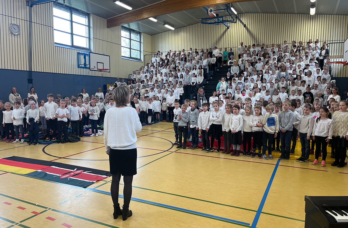 Pressebild-Schüler-und-Lehrer-begrüßen-stehend-die-deutsch-kenianische-Flagge-web